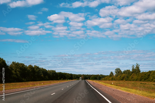 highway going into the distance. Gorgeous view of highway going into distance through forests against background of blue sky with white clouds © oksanamedvedeva