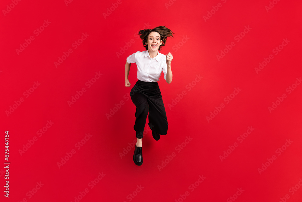 Full length photo of cheerful excited young woman wear uniform jump up runner isolated on red color background Full length photo of cheerful excited young woman wear uniform jump up runner isolated on red color background