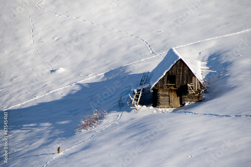 A cozy wooden cabin nestled in a vast snowy field © Picstocker