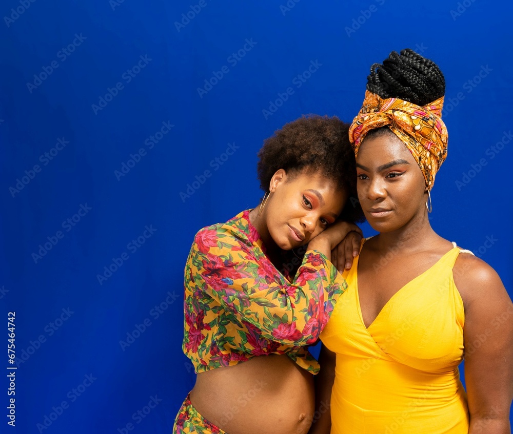 Portrait of two women against blue background. Portrait of two women against blue background.