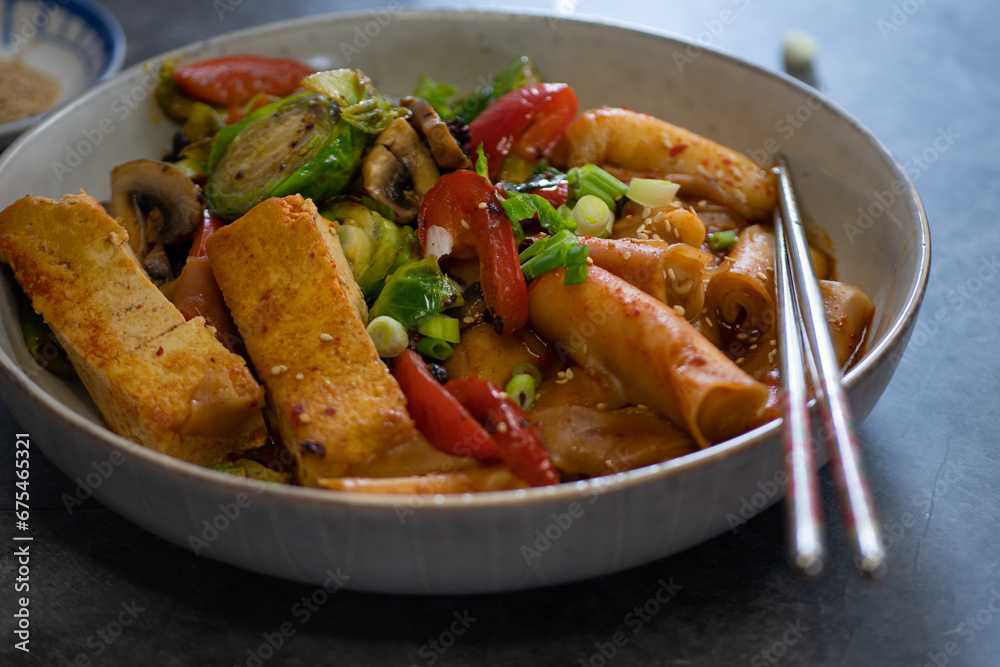 Tteokbokki- korean rice cakes and vegetable stew served in white bowl, traditional steel chopsticks. Tteokbokki- korean rice cakes and vegetable stew served in white bowl, traditional steel chopsticks.