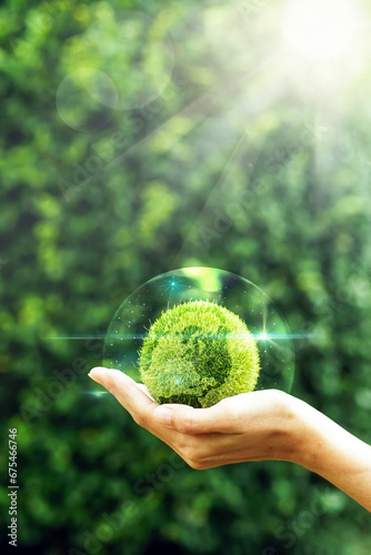 Hand holding a green grass earth globe in bubble with light reflection, flare light on natural background for Friendly globe day, environmental management, business concept.Banner.Copy space.Vertical.