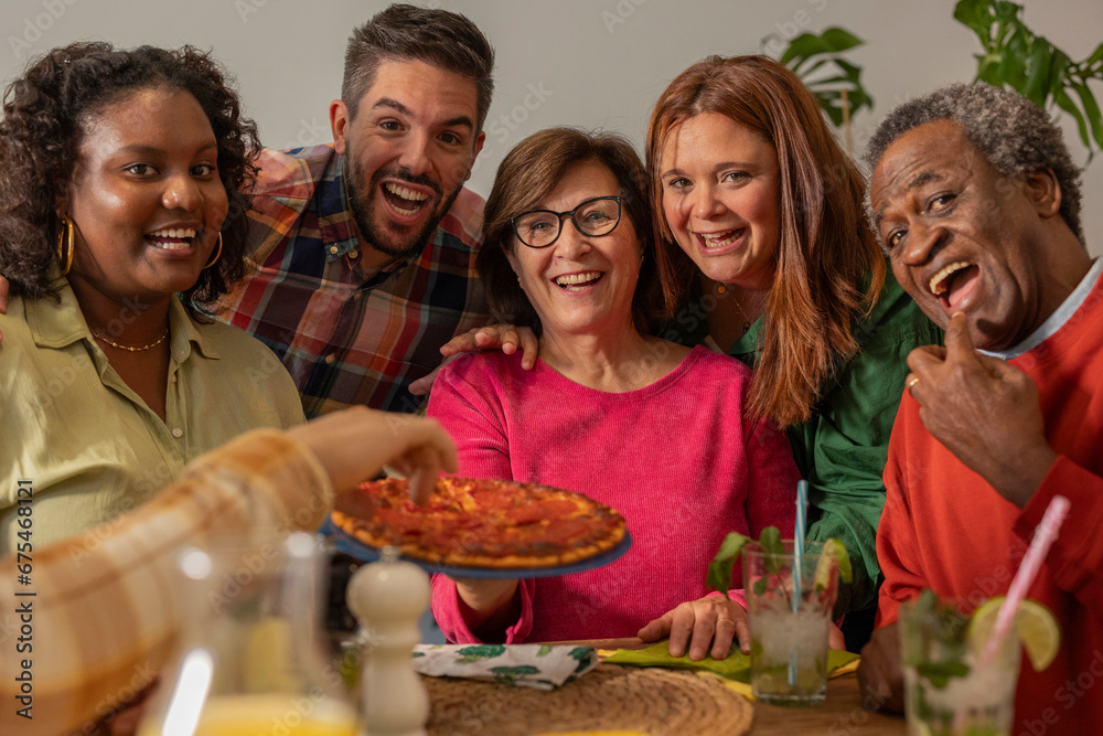 Group of multiracial friends, of different ages, generations, celebrating a pizza dinner in a restaurant, selfie with smart phone