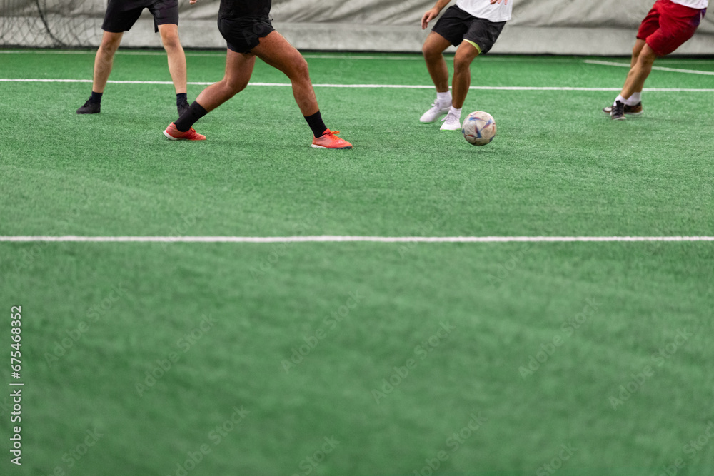 Five-a-side soccer players playing game in indoor stadium on artificial turf. Five-a-side soccer players playing game in indoor stadium on artificial turf.