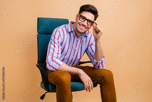 Photo of nice cheerful man wear trendy clothes sitting chair holding eyeglasses interviewing applicant isolated on beige color background