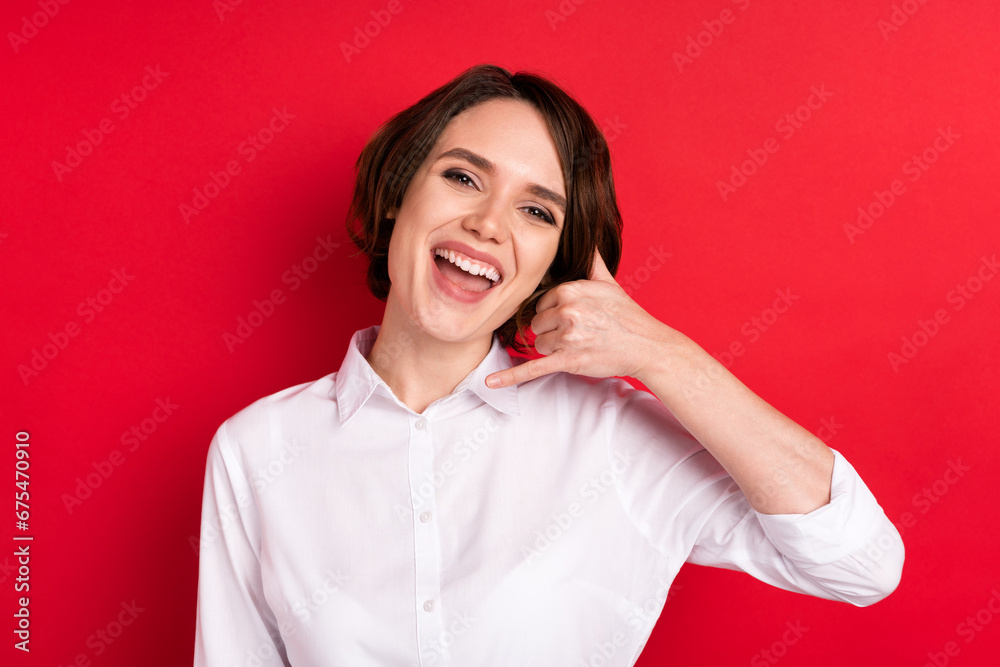 Photo of lovely happy nice young woman hold hands make call me sign smile isolated on red color background Photo of lovely happy nice young woman hold hands make call me sign smile isolated on red color background
