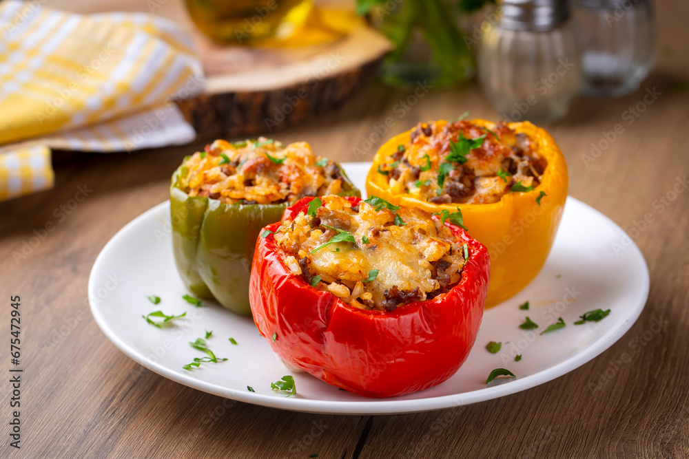 Stuffed peppers, halves of peppers stuffed with rice, dried tomatoes, herbs and cheese in a baking dish on a blue wooden table, top view. (Turkish name; biber dolmasi)