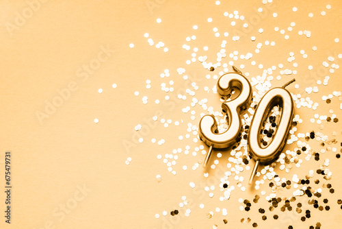 30 years celebration festive background made with golden candles in the form of number Thirty lying on sparkles. Universal holiday banner with copy space. photo