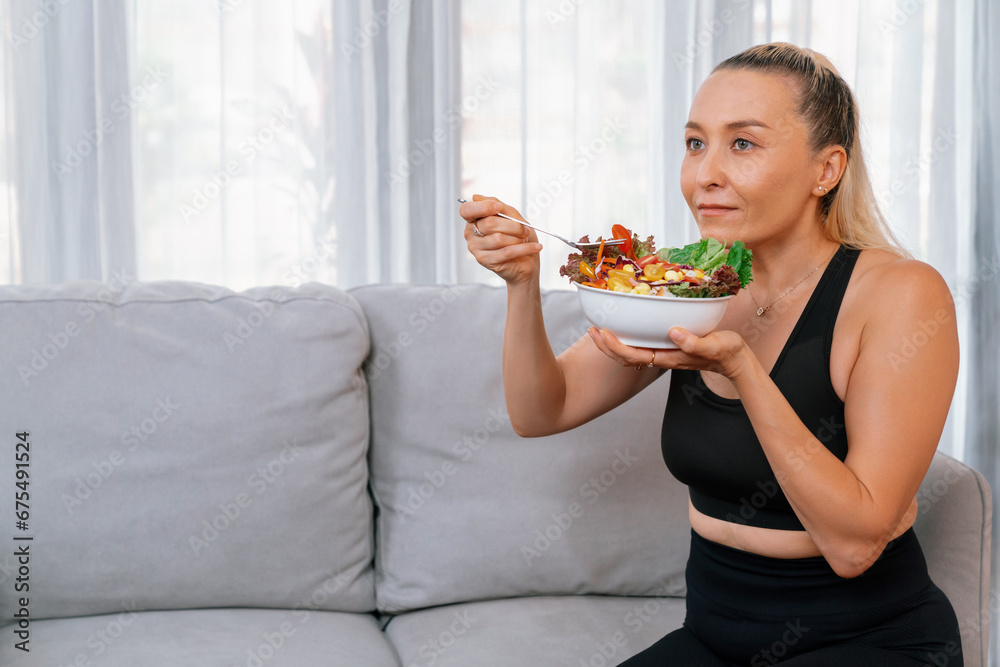 Healthy senior woman in sportswear holding a bowl of fruit and vegetable. Vegan lifestyle and healthy cuisine nutrition for fitness body physique concept. Clout