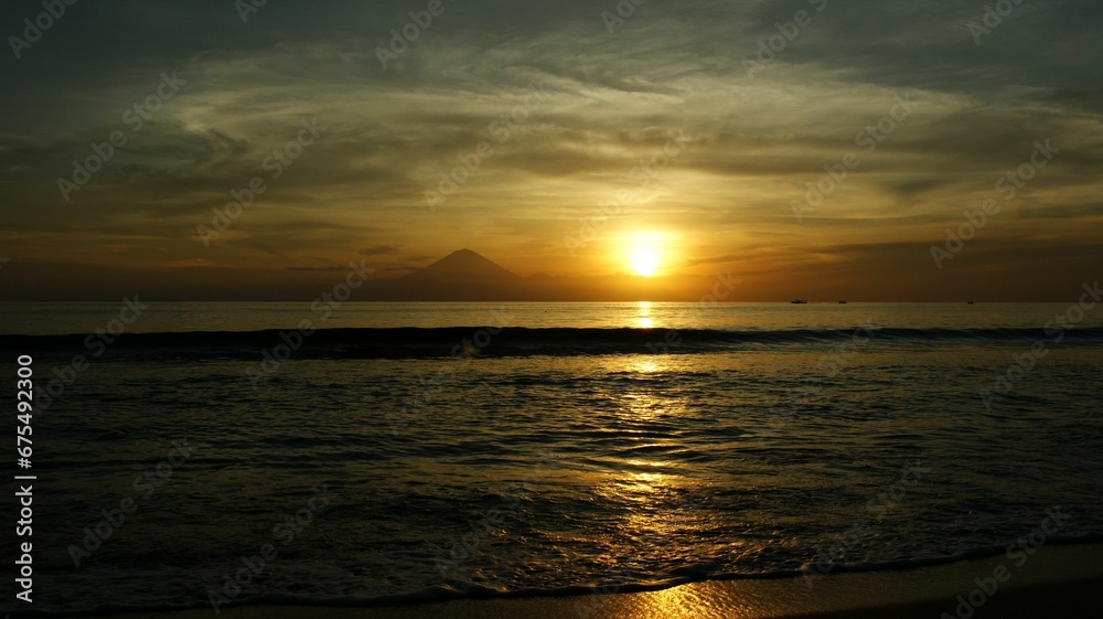Serene sea at sunset with a mountain silhouetted in the background. Lombok, Indonesia. Serene sea at sunset with a mountain silhouetted in the background. Lombok, Indonesia.