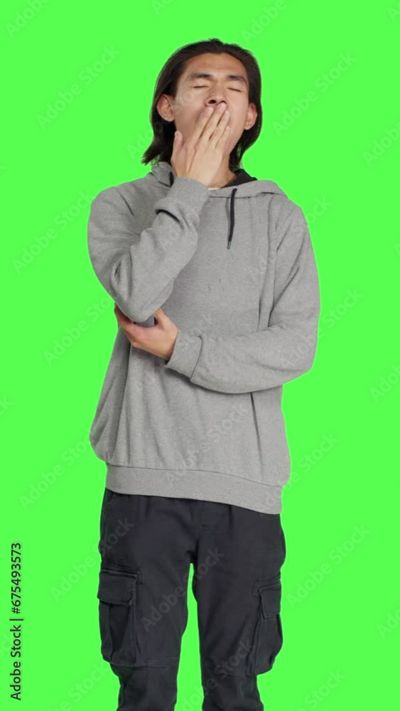 Front view of male model feeling tired and yawning after not getting enough sleep, posing with fatigue over greenscreen template. Young asian person being extremely sleepy and exhausted, fall asleep. Front view of male model feeling tired and yawning after not getting enough sleep, posing with fatigue over greenscreen template. Young asian person being extremely sleepy and exhausted, fall asleep.