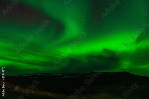 Lush green aurora borealis illuminating the night sky above a majestic mountain range