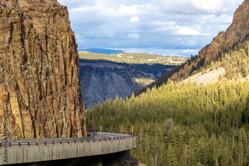 grand loop road at golden gate entering kingman pass in yellowstone national park, image shows the road curving round and descending along the cliff face with the forest background, october 2023