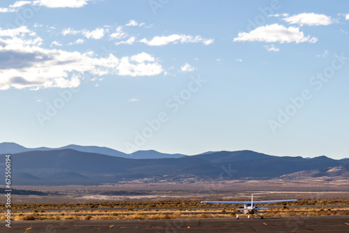 Propeller plane parked at the airport. Small airfield in front of high mountains, sunset over airfield and the light aircraft. October 2023