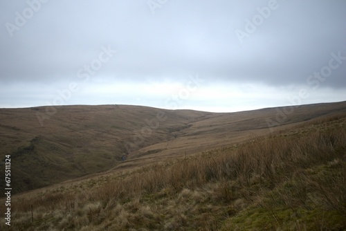 Scenic view of a valley with green hills on a cloudy day in Wales, UK