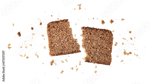 Broken slice of dark rye bread with crumbs flying isolated on white photo