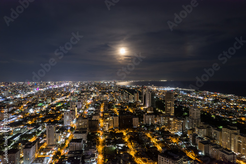 Beautiful aerial Night view of the illuminated city of Santo Domingo - Dominican Republic with is Parks, buildings, suburbs ,turquoise Caribbean ocean, parks and malecon