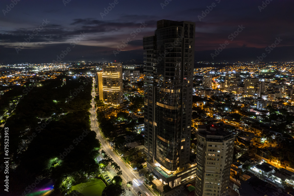 Fototapeta premium Beautiful aerial Night view of the illuminated city of Santo Domingo - Dominican Republic with is Parks, buildings, suburbs ,turquoise Caribbean ocean, parks and malecon