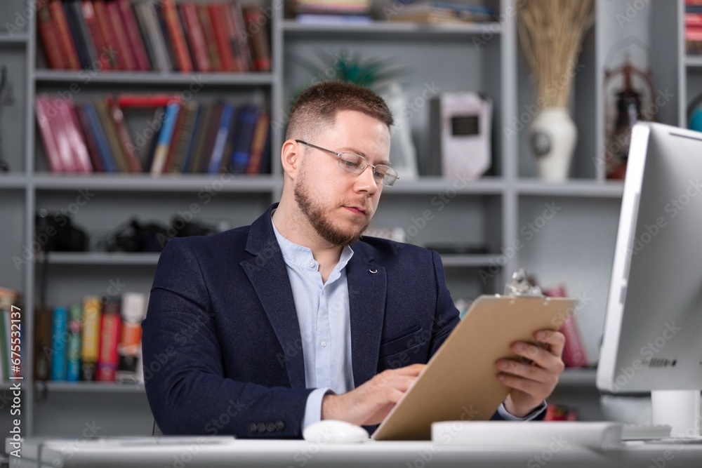 Male psychoanalyst with clipboard working on pc Male psychoanalyst with clipboard working on pc