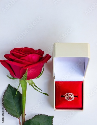 Red rose and white box with jewelry on a white background.