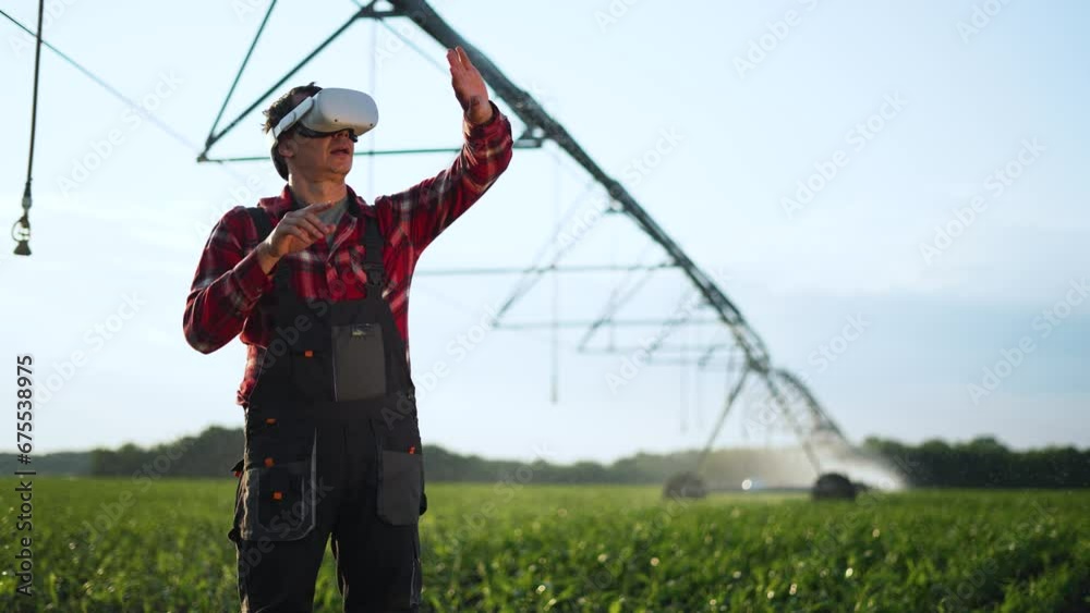 Agriculture.Farmer wearing virtual reality glasses in cornfield. Automatic watering system for plants in drought. Farmer irrigates green fields with help of modern technologies. Farm irrigation system