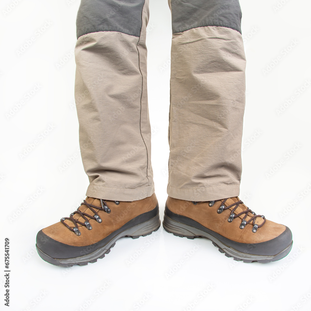 Trekking boots for hiking on the legs of a tourist on a white background. Equipment for travel and hiking Trekking boots for hiking on the legs of a tourist on a white background. Equipment for travel and hiking