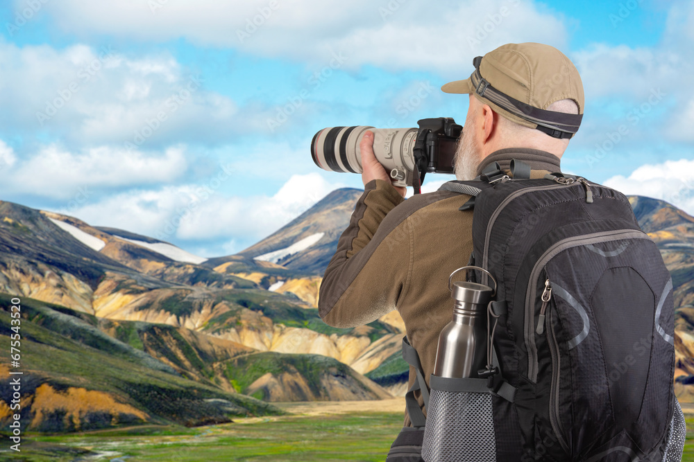man tourist photographer with a backpack photographs the beauty of nature in the mountains. nature hikes in the mountains