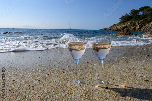 Fototapeta Naklejka Na Ścianę i Meble -  Summer time in Provence, two glasses of cold rose wine on sandy beach near Saint-Tropez in sunny day, Var department, France