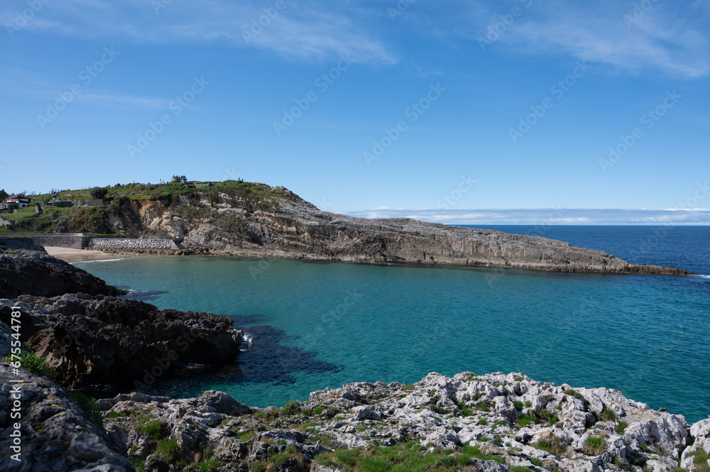 View on rocks on Playa de Toro in Llanes, Green coast of Asturias, North Spain with sandy beaches, cliffs, hidden caves, forests and mountains.