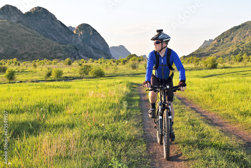 cyclist rides on the road in a field on a bright sunny day.