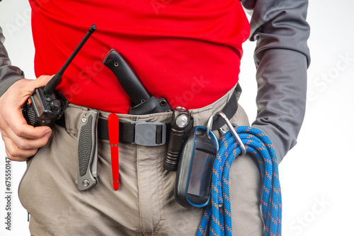 walkie-talkie, flashlight, knife, GPS navigator, climbing rope on the belt of the tourist trekking pants. equipment for tourism and travel. EDC items.