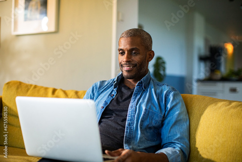 Smiling middle aged man using laptop on couch photo