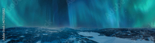 Very wide scenic aerial night skies panorama on mountains winter forest, lake with snow mobile traces, northern green lights. Scandinavian night winter landscape, Norway, Sweden