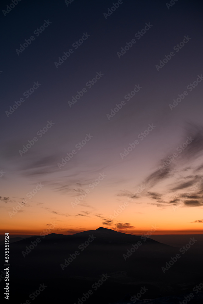 Vertical shot with incredible colors of a sunset sky over distant silhouetted mountains
