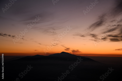 Horizontal shot with incredible colors of a sunset sky over distant silhouetted mountains. © fesenko