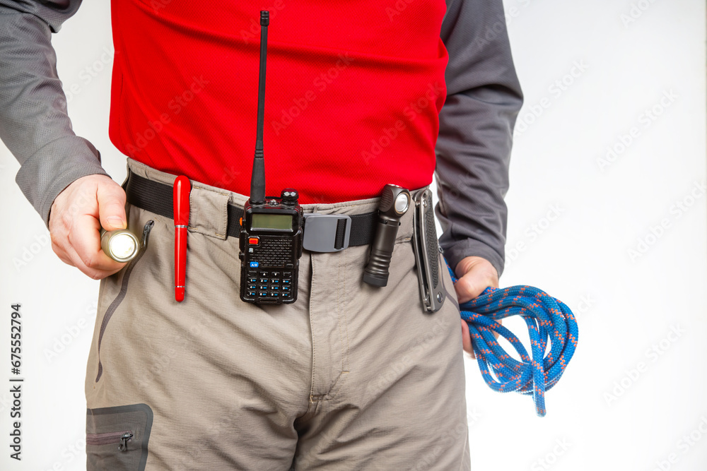 Pen, walkie-talkie, knife and flashlight with clips on the waistband of trekking pants. EDC items Pen, walkie-talkie, knife and flashlight with clips on the waistband of trekking pants. EDC items