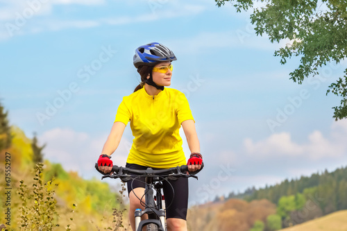 Beautiful woman cyclist rides on the field on a bicycle. Healthy lifestyle and sport.