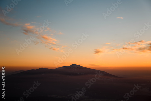 Aerial view of mountains at sunrise in winter. Mountain peak in fog.