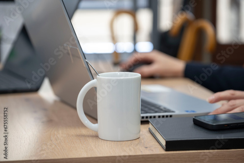tasse ou mug blanc posé sur un bureau à coté d'un ordinateur portable photo