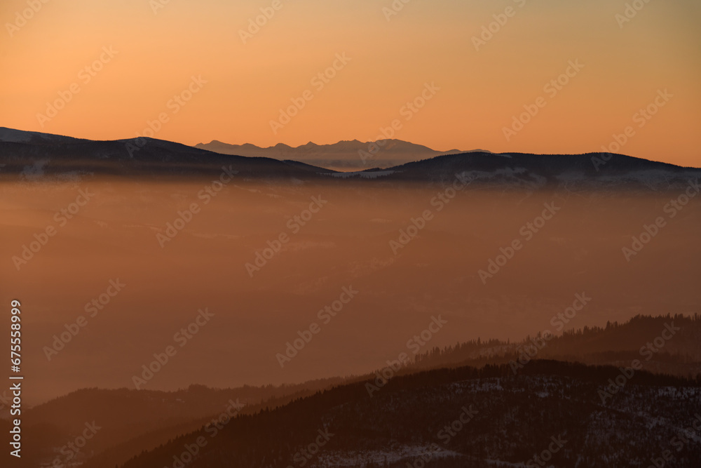 Amazing view of winter landscape with hills and mountains silhouettes during sunrise Amazing view of winter landscape with hills and mountains silhouettes during sunrise