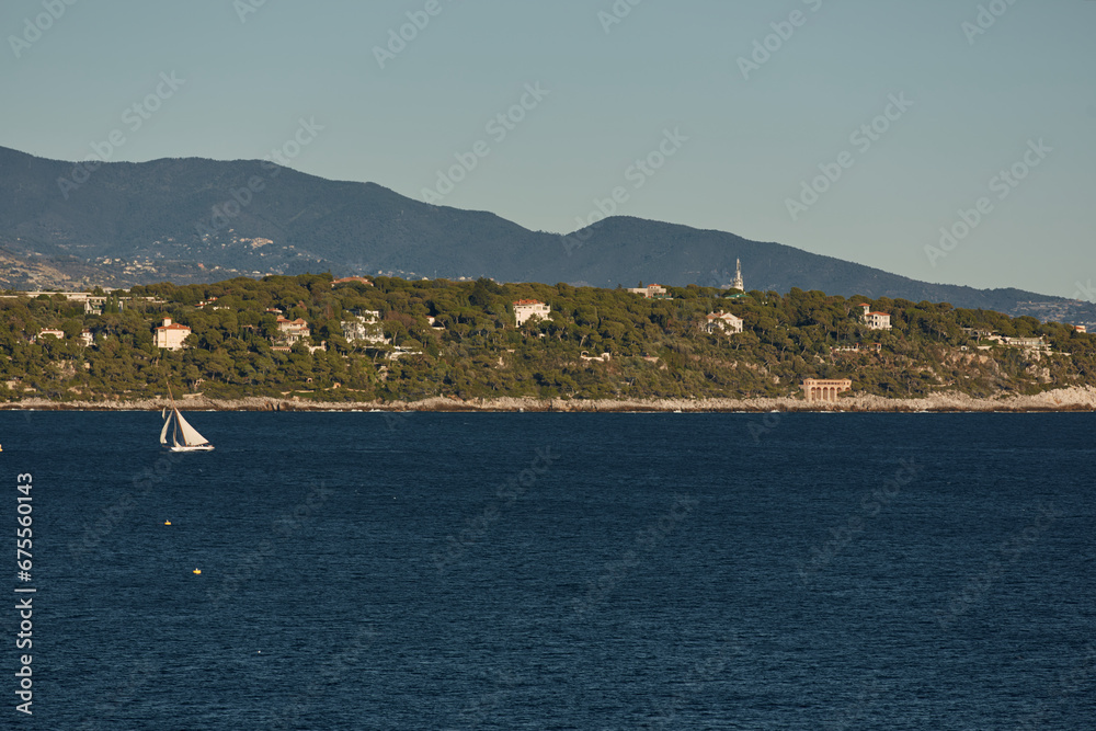 Monaco, huge sail yacht is in sea at sunset, island is nearby, wealth life of billionaires, mountains on background