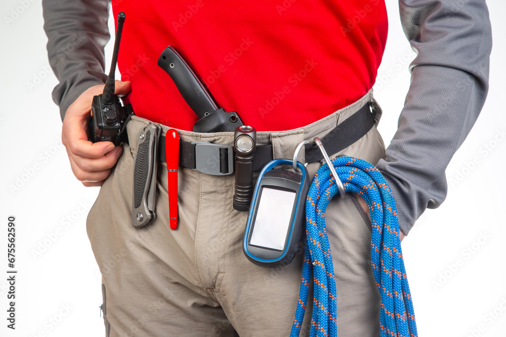 walkie-talkie, flashlight, knife, GPS navigator, climbing rope on the belt of the tourist trekking pants. equipment for tourism and travel. EDC items. walkie-talkie, flashlight, knife, GPS navigator, climbing rope on the belt of the tourist trekking pants. equipment for tourism and travel. EDC items.