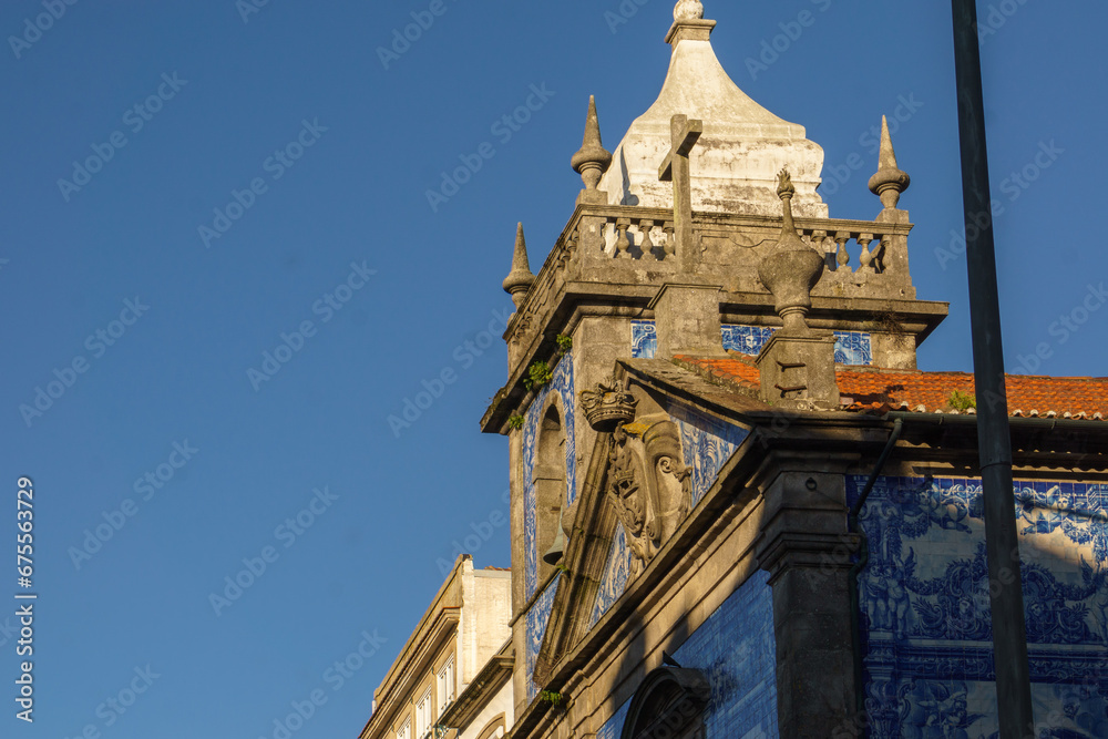 Tower of Chapel of Souls or Capela das Almas with beautiful blue white azulejo tiles facade illuminated by golden sunlight in Porto, Portugal