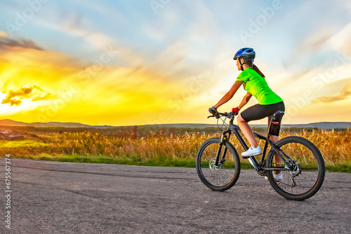 Fototapeta Naklejka Na Ścianę i Meble -  Beautiful woman cyclist rides a bicycle on a road. Healthy lifestyle and sports. Leisure and hobbies