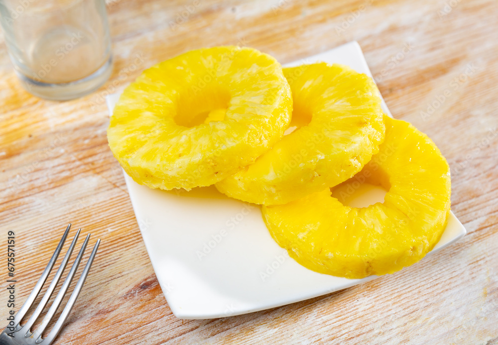 Ripe jucy pineapple sliced and served on white plate.