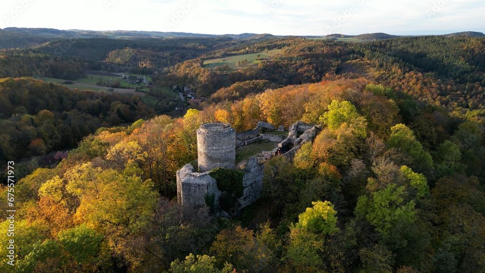Naklejka premium An aerial view of the beautiful ruins of Wlen Castle, in the town of Wlen, Lower Silesia in Poland, at the foot of the Karkonosze Mountains on the Bobr River, in autumn just before sunset.