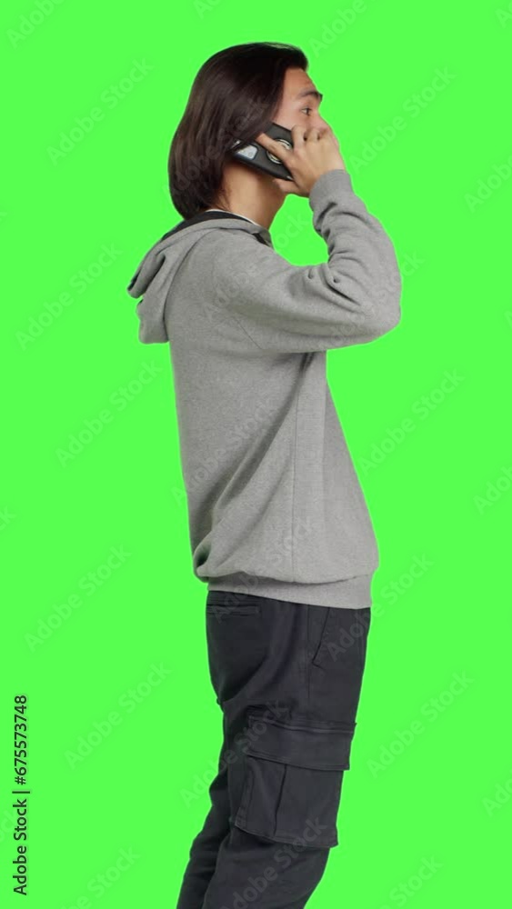 modern person chatting on phone call against greenscreen backdrop, using smartphone line to talk to his friends in studio. Young adult answering call to have remote conversation. modern person chatting on phone call against greenscreen backdrop, using smartphone line to talk to his friends in studio. Young adult answering call to have remote conversation.