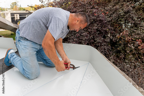 Foto Tinsmith worker using scissors to cut the metal sheet for roofing