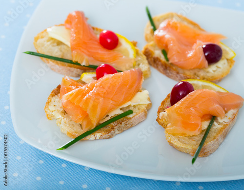 Close up image of exquisitely served canapes with salmon, butter and cranberries photo
