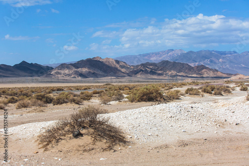 View of Mojave Desert national reserve landscape, an arid rain-shadow desert, California, United States of America, summer sunny day with road, mountains, sand dunes and a blue sky photo